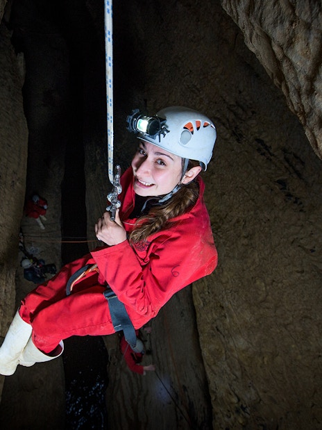 Caver descending in Waitomo cave during Black Abyss tour with zip lining and rafting.
