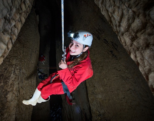 Caver descending in Waitomo cave during Black Abyss tour with zip lining and rafting.