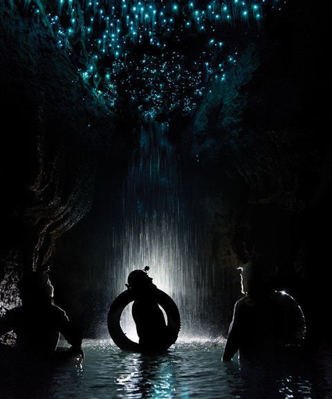 Adventurers rafting under glowworms in Waitomo Cave, New Zealand.
