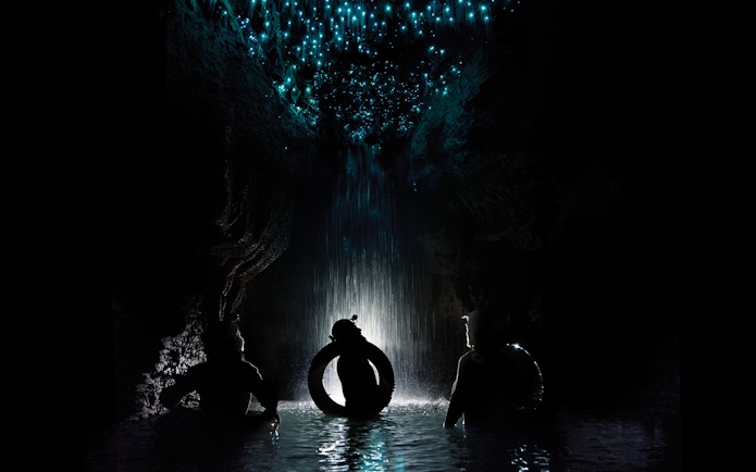 Adventurers rafting under glowworms in Waitomo Cave, New Zealand.