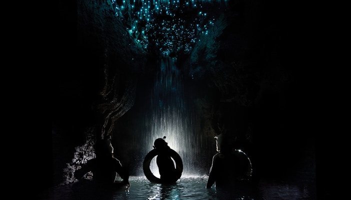 Adventurers rafting under glowworms in Waitomo Cave, New Zealand.