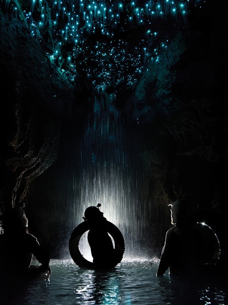 Adventurers rafting under glowworms in Waitomo Cave, New Zealand.