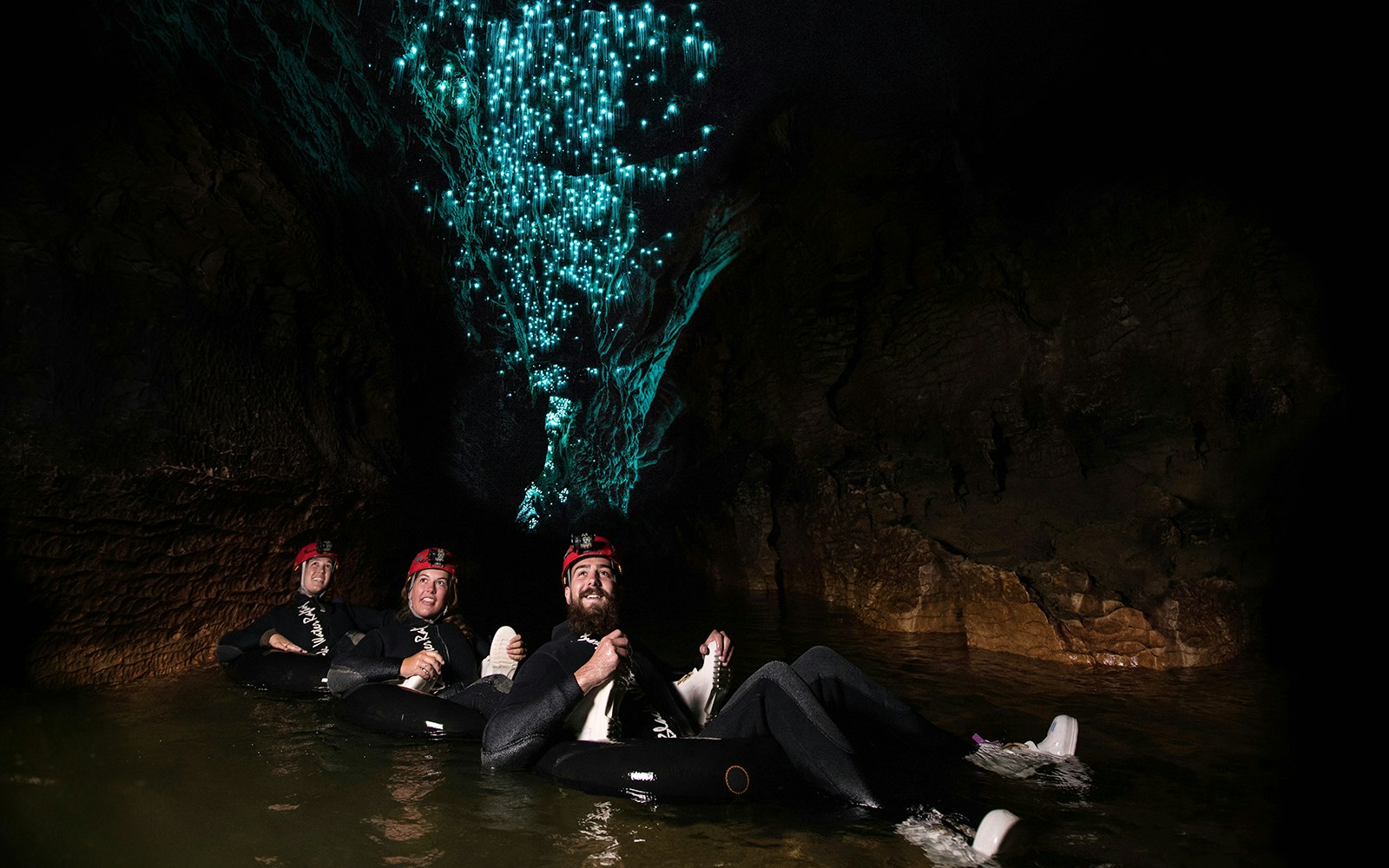 Adventurers tubing under glowworms in Waitomo cave during Black Water Rafting experience.
