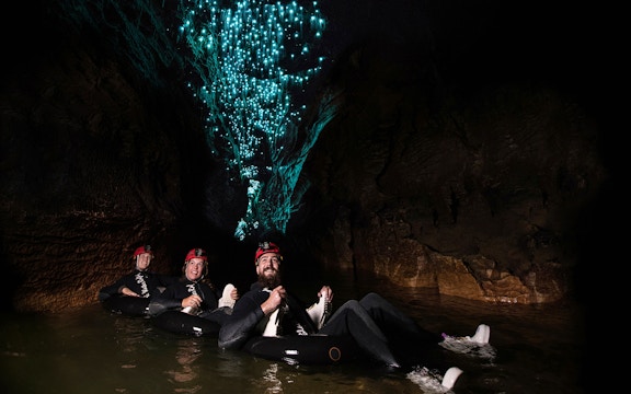 Adventurers tubing under glowworms in Waitomo cave during Black Water Rafting experience.