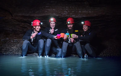 Group enjoying Black Water Rafting in Waitomo cave, wearing helmets and wetsuits.