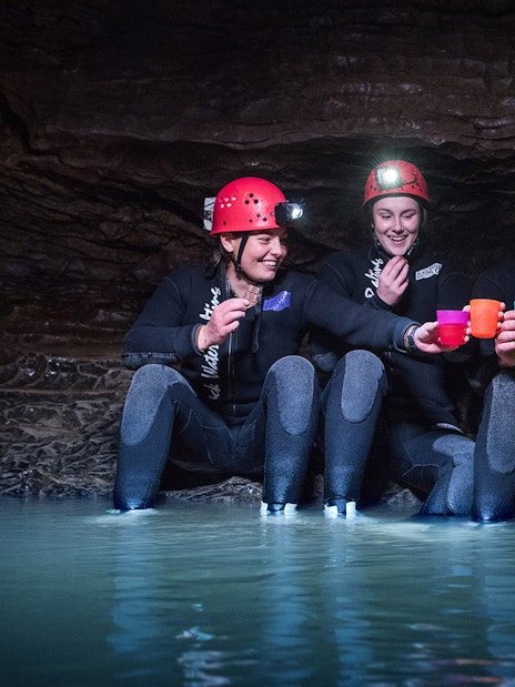 Group enjoying Black Water Rafting in Waitomo cave, wearing helmets and wetsuits.