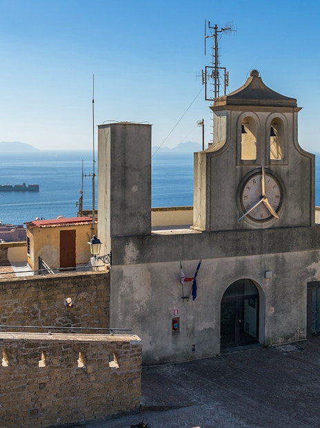 Castel Sant'Elmo terrace with clock tower and sea view, Naples, Italy.