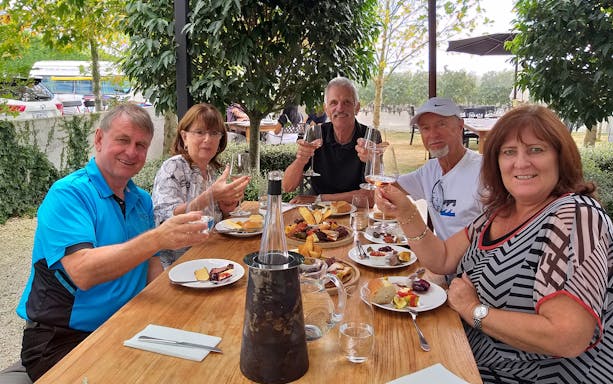 Group enjoying wine and food at a vineyard in Martinborough during a full-day tour from Wellington.