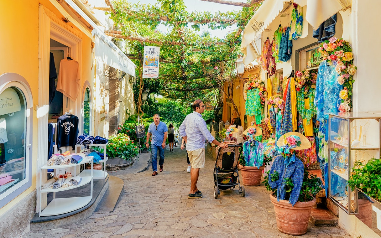 Street in Positano with colorful shops and tourists exploring during a guided tour from Naples.