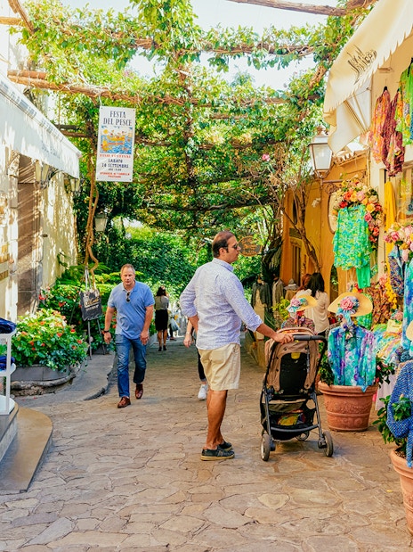 Street in Positano with colorful shops and tourists exploring during a guided tour from Naples.