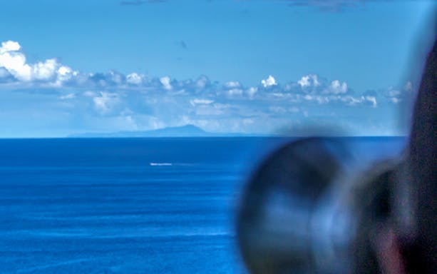 View of the ocean with distant land, seen through a telescope on the Azorean Whalers Heritage Tour.