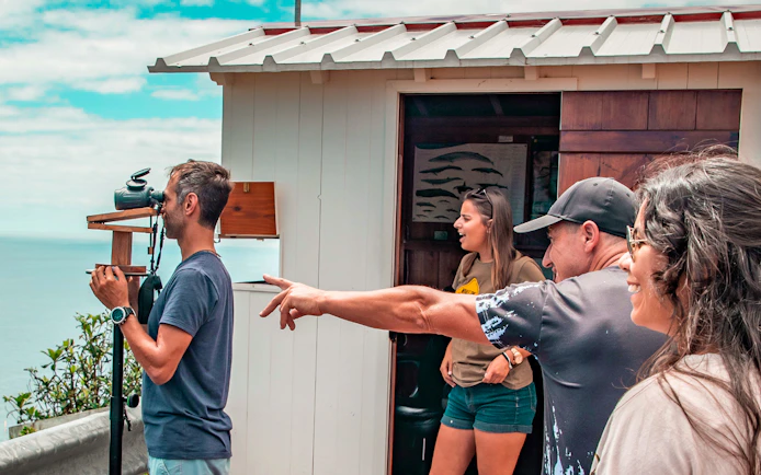 Tourists observing the ocean with binoculars on the Azorean Whalers Heritage Tour.