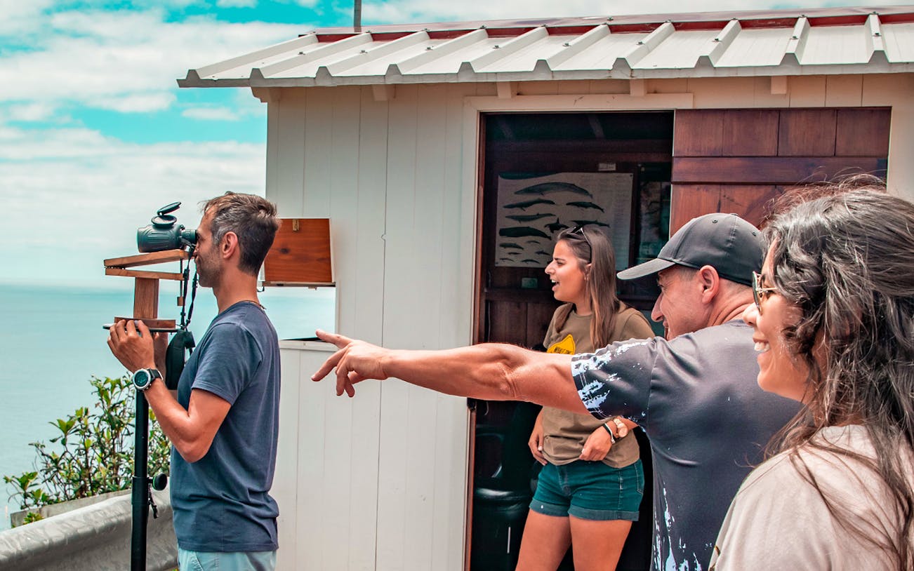 Tourists observing the ocean with binoculars on the Azorean Whalers Heritage Tour.