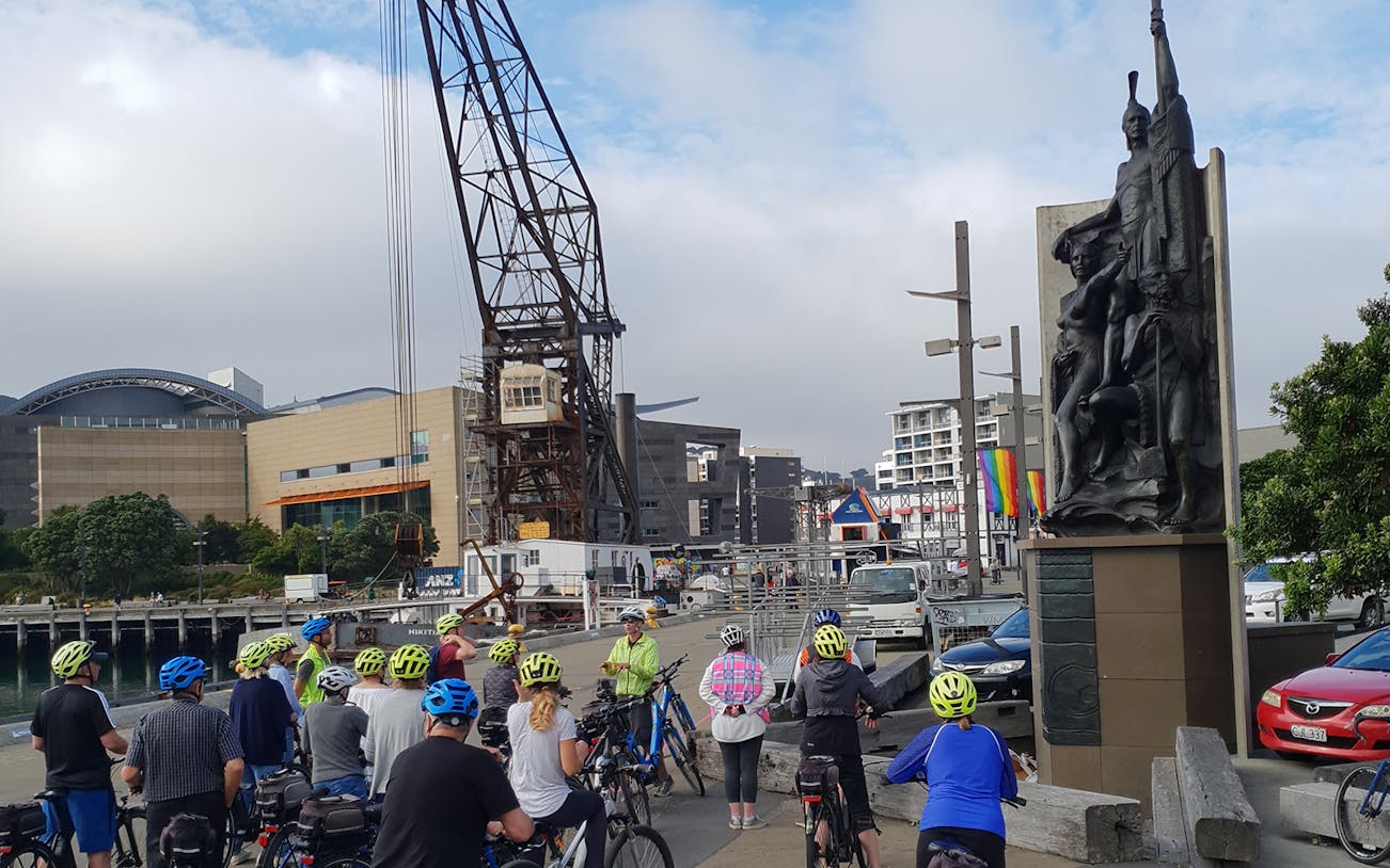 Cyclists gather near a waterfront sculpture during a Wellington guided bike tour.