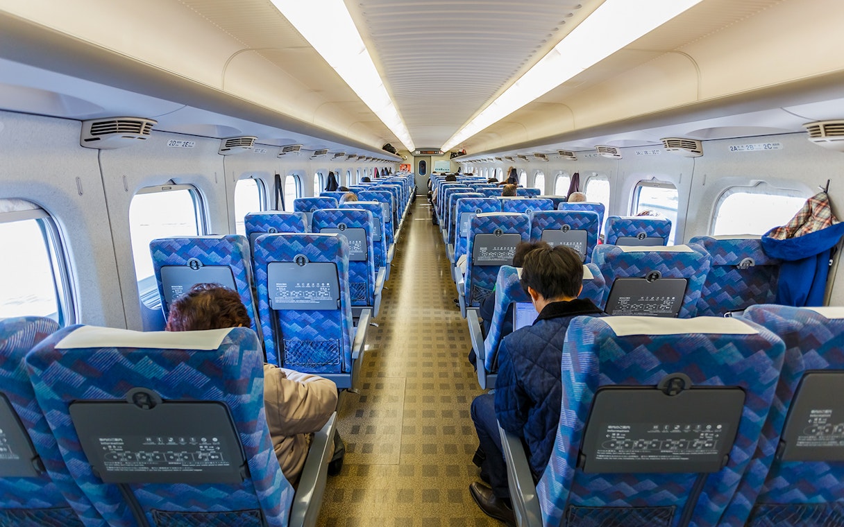 Interior of a JR East train in the Tohoku area with passengers seated.