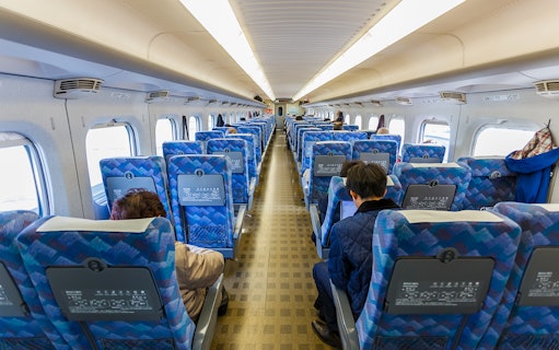 Interior of a JR East train in the Tohoku area with passengers seated.