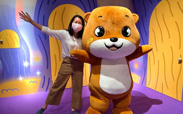 Person posing with Otah mascot at Otah & Friends: Camp Stardust exhibit.