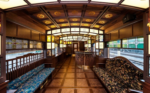 Luxurious interior of a vintage train in Southern Kyushu, featuring ornate woodwork and stained glass.