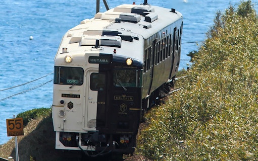 Train traveling along the coast in Southern Kyushu, Japan, with ocean view.