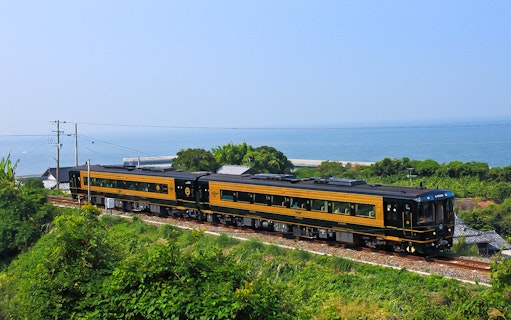 Train traveling along the coast in Southern Kyushu, Japan, with ocean view.