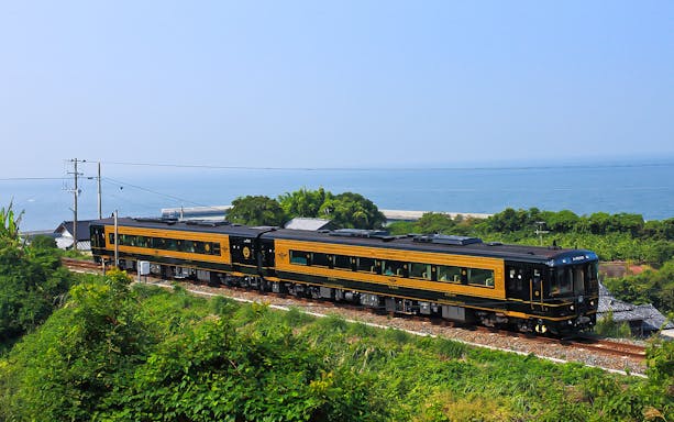 Train traveling along the coast in Southern Kyushu, Japan, with ocean view.