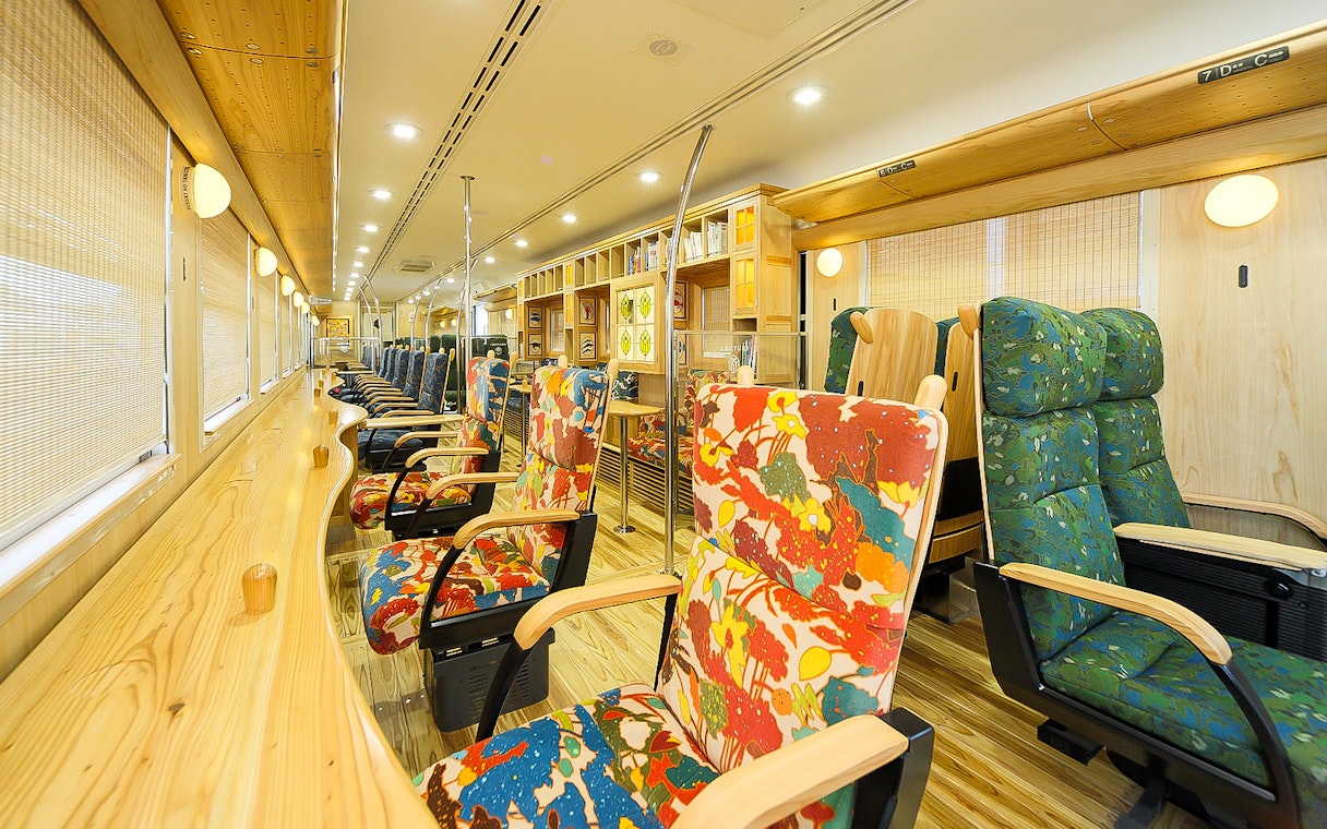 Colorful train interior with patterned seats on the Southern Kyushu Area Pass route.