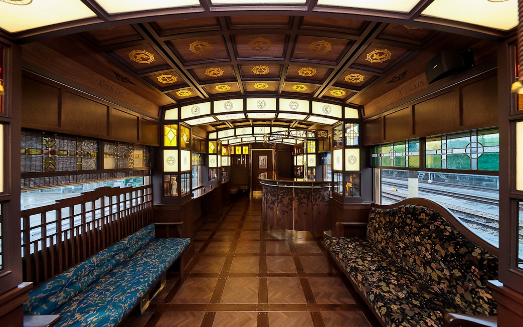 Luxurious interior of a JR North Kyushu train with wooden decor and stained glass windows.