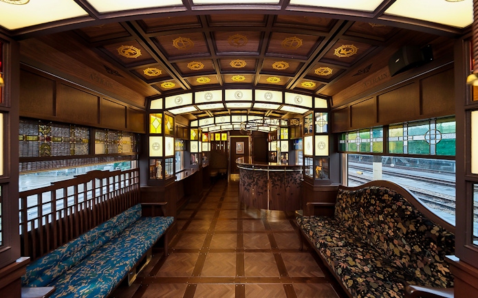 Luxurious interior of a JR North Kyushu train with wooden decor and stained glass windows.
