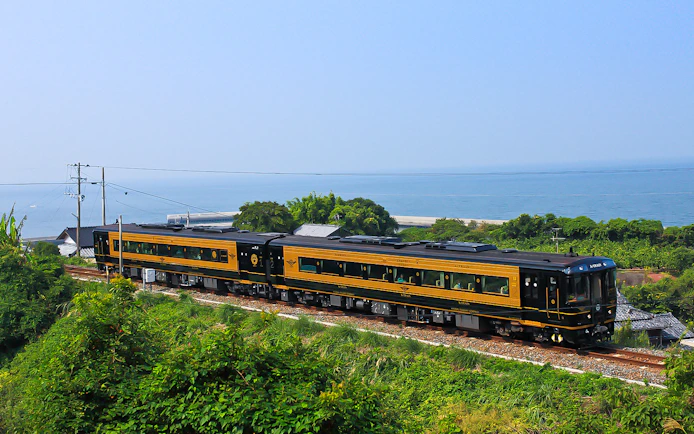 Train traveling along Kyushu coast with ocean view, JR North Kyushu Rail Pass.