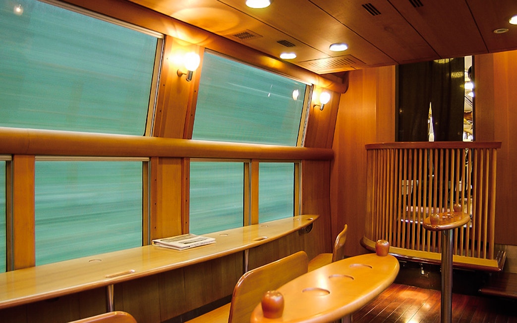 Interior of JR North Kyushu train with wooden decor and large windows.