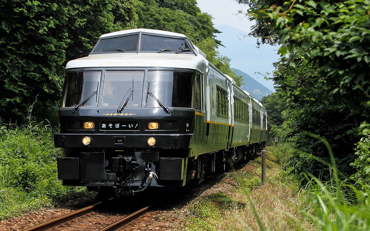 Train traveling through lush greenery in Kyushu, Japan, associated with JR North Kyushu Rail Pass.