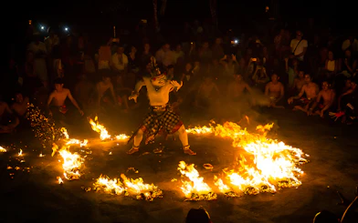 Performer in traditional costume surrounded by fire at Uluwatu Kecak & Fire Dance Show, Bali.