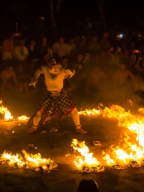 Performer in traditional costume surrounded by fire at Uluwatu Kecak & Fire Dance Show, Bali.
