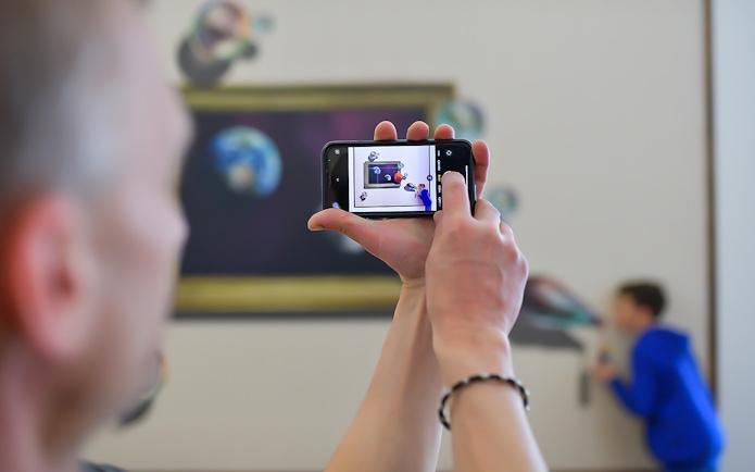 Person photographing illusion art at Illusion Art Museum Prague.