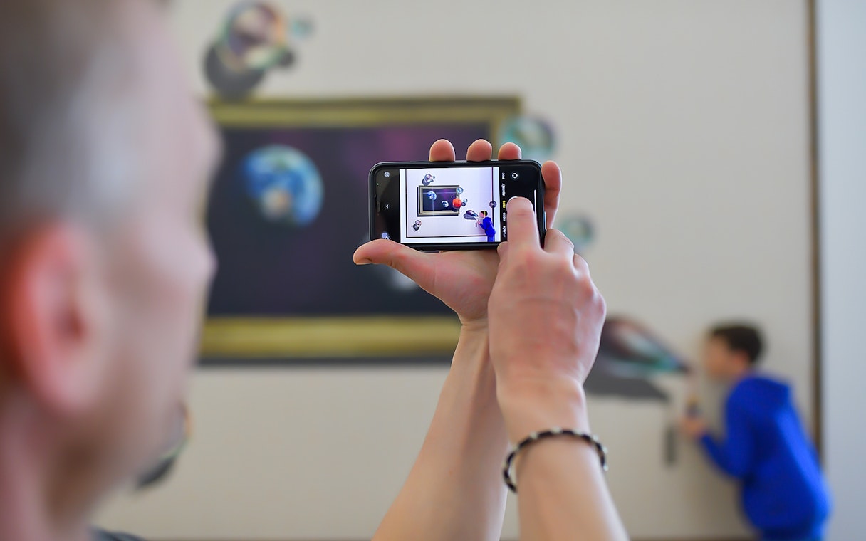 Person photographing illusion art at Illusion Art Museum Prague.