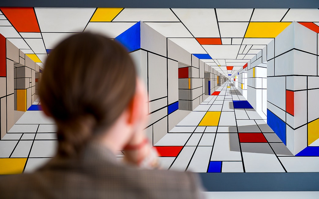 Viewer observing geometric optical illusion at Illusion Art Museum Prague.