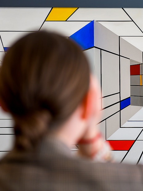 Viewer observing geometric optical illusion at Illusion Art Museum Prague.