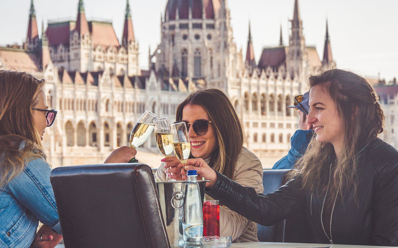Guests toasting with champagne on a New Year's Day cruise in Budapest, Hungarian Parliament in view.