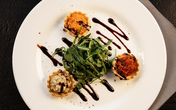 Gourmet appetizers with arugula and balsamic drizzle on New Year's Day cruise in Budapest.