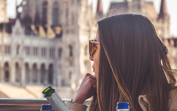 Woman enjoying Budapest cruise with view of historic building.
