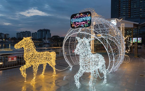 Light sculptures of horses and carriage at 99 Wonderland Park during evening.