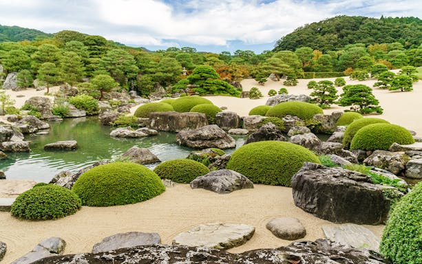 Japanese garden with manicured shrubs and rocks in San’in-Okayama area.