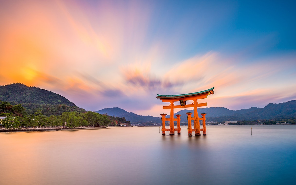 Torii gate at Itsukushima Shrine in Hiroshima during sunset, viewed from the water.
