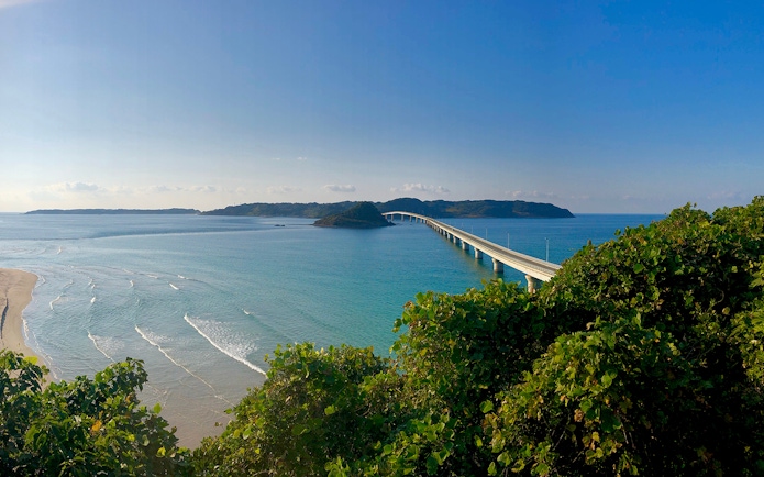 Bridge over turquoise sea in Yamaguchi, Japan, viewed from a lush green hill.