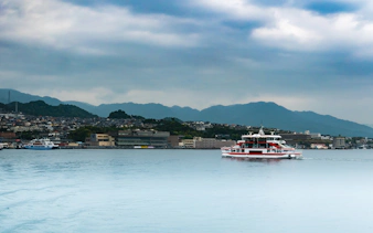Ferry crossing Seto Inland Sea with Hiroshima cityscape and mountains in background.