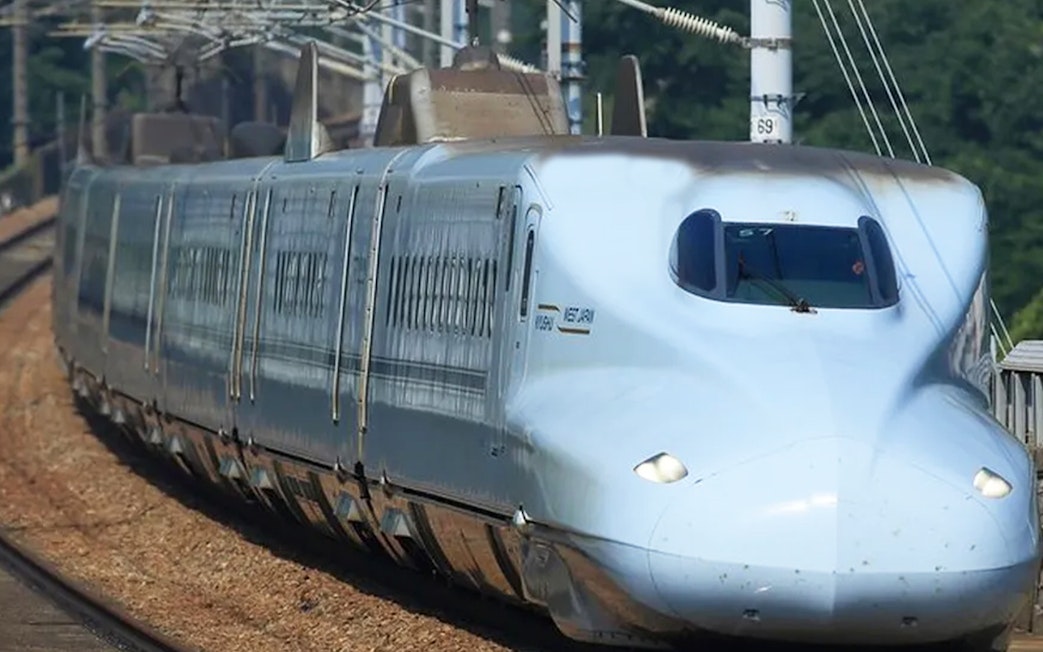 Shinkansen bullet train traveling through Hiroshima, Japan, on a sunny day.
