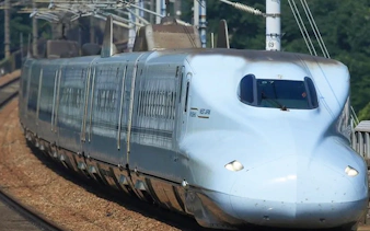 Shinkansen bullet train traveling through Hiroshima, Japan, on a sunny day.
