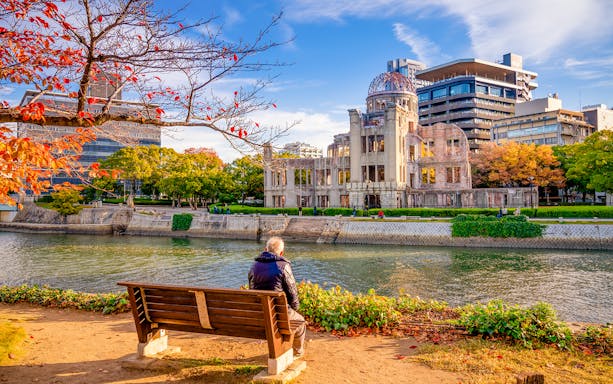 Hiroshima Peace Memorial with autumn foliage, viewed from across the river.