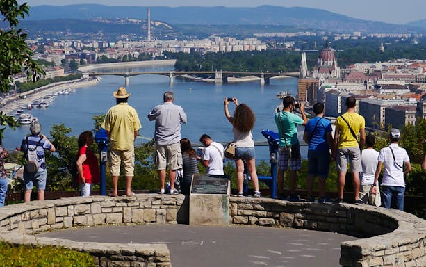 Tourists viewing Budapest skyline and Danube River from a hilltop during a guided bus tour.