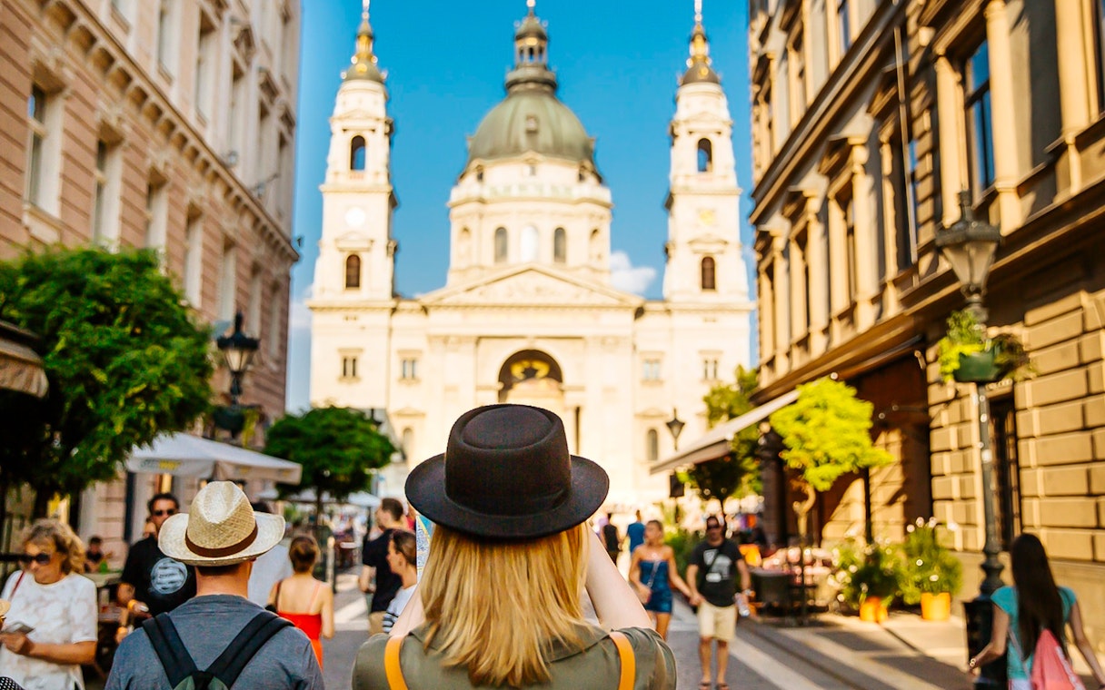 Tourists walking towards St. Stephen's Basilica in Budapest during a guided bus tour.